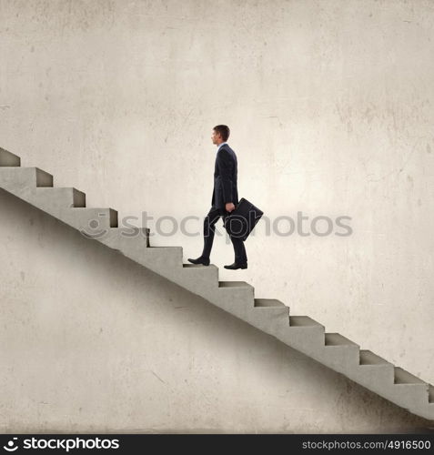 Up the career ladder. Young businessman walking up on staircase representing success concept