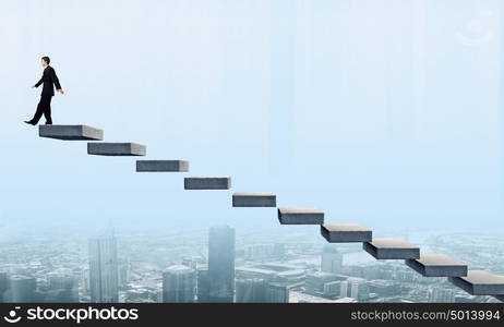 Up the career ladder. Young businessman walking up on staircase representing success concept