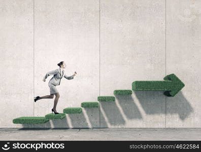 Up the career ladder. Young businesswoman reaching up staircase as symbol of growth and progress