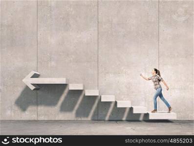 Up the career ladder. Young businesswoman reaching up staircase as symbol of growth and progress