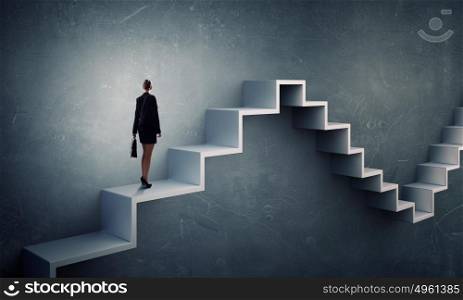 Up the career ladder. Young businesswoman reaching up staircase as symbol of growth and progress