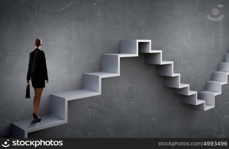 Up the career ladder. Young businesswoman reaching up staircase as symbol of growth and progress