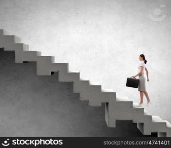 Up the career ladder. Young businesswoman walking up on staircase representing success concept