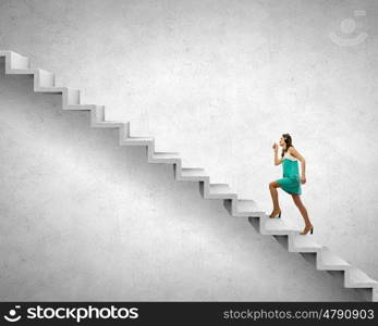 Up the career ladder. Young businesswoman walking up on staircase representing success concept