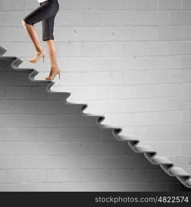 Up the career ladder. Young businesswoman walking up on staircase representing success concept