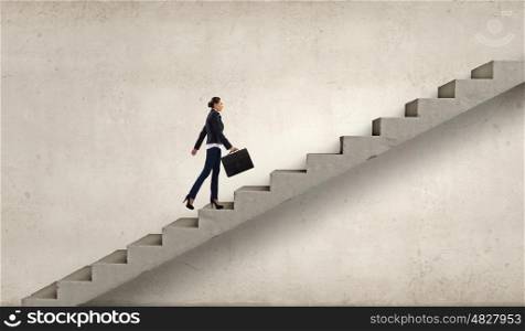 Up the career ladder. Young businesswoman walking up on staircase representing success concept
