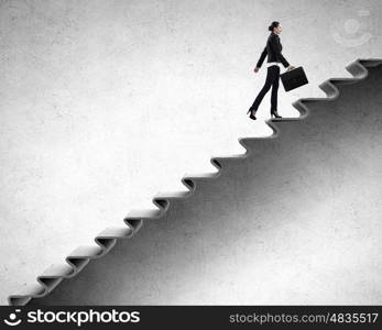 Up the career ladder. Young businesswoman walking up on staircase representing success concept