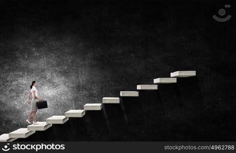 Up the career ladder. Young businesswoman walking up staircase representing success concept