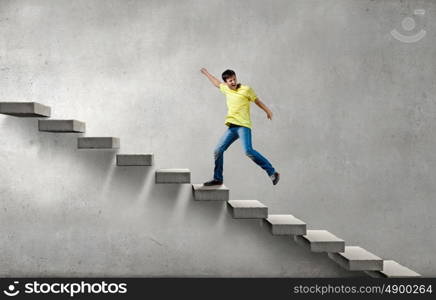 Up the career ladder. Young man walking up on staircase representing success concept