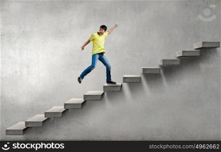 Up the career ladder. Young man walking up on staircase representing success concept