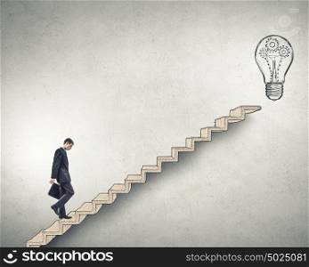 Up the career ladder. Young tired businessman walking up on staircase representing successful idea concept