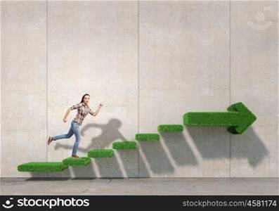Up the staircase. Young woman running on green grass staircase
