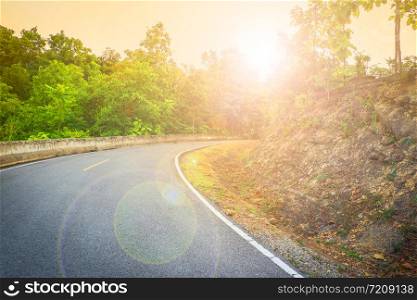 Uphill road curve with sunlight in the morning and tree in the roadside