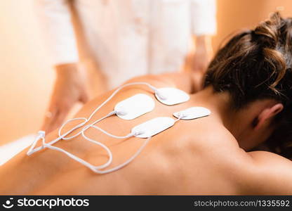 Upper Back Physical Therapy with TENS Electrode Pads, Transcutaneous Electrical Nerve Stimulation. Therapist Positioning Electrodes onto Patient&rsquo;s Upper Back. Upper Back Physical Therapy with TENS Electrode Pads, Transcutaneous Electrical Nerve Stimulation