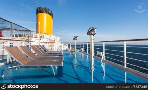 upper deck of cruise liner with empty sunbathing chairs in summer morbning
