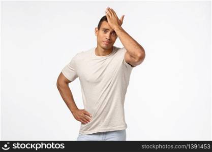 Upset and disappointed gloomy handsome guy in casual t-shirt, punch forehead, facepalm motion, smirk displeased, someone let him down, forgot important task, standing frustrated white background.. Upset and disappointed gloomy handsome guy in casual t-shirt, punch forehead, facepalm motion, smirk displeased, someone let him down, forgot important task, standing frustrated white background