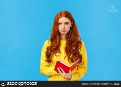 Upset and uneasy, sad cute redhead girl in yellow sweater, sulking frowning and looking camera depressed, holding red notebook, read someones diary, sharing thoughts on paper, distressed.. Upset and uneasy, sad cute redhead girl in yellow sweater, sulking frowning and looking camera depressed, holding red notebook, read someones diary, sharing thoughts on paper, distressed
