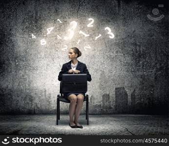 Upset businesswoman. Young upset businesswoman with suitcase sitting on chair