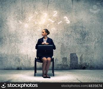 Upset businesswoman. Young upset businesswoman with suitcase sitting on chair