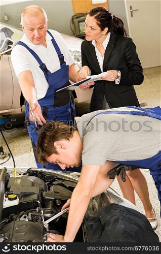 Upset female supervisor showing papers to car mechanic