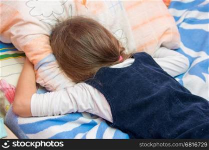 Upset little girl crying with his face buried in the pillow