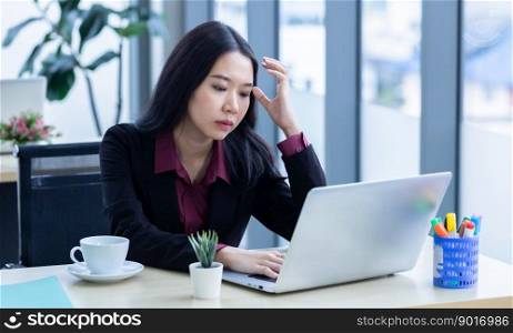 Upset thoughtful Young Asian business woman stress in the workplace working with laptop computer of Office staff are not happy in with working colleagues behind in the office