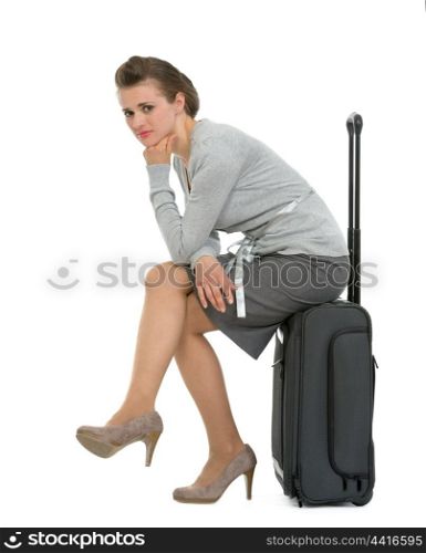 Upset traveling woman sitting on suitcase