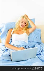 Upset woman sitting in bed with computer