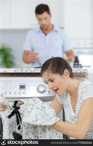 upset woman sitting next to washing machine