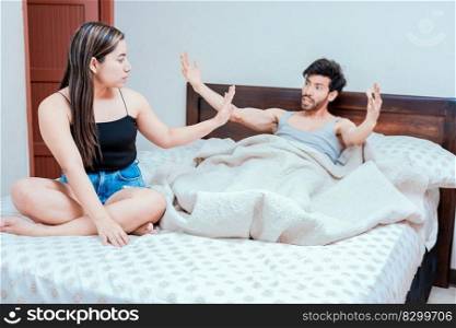 Upset woman with husband in bedroom bed, Husband fighting with his wife in bed.  Young couple arguing in bed room. Concept of couple problems in bed