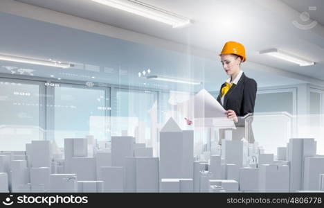 Urban construction. Woman engineer in hardhat examining construction project