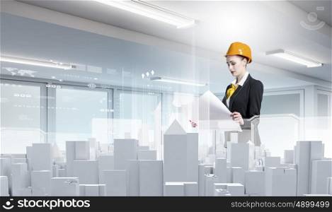 Urban construction. Woman engineer in hardhat examining construction project