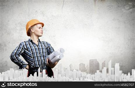 Urban construction. Young blond woman builder with projects in hand