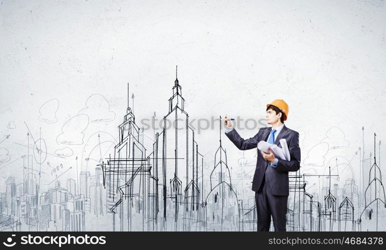 Urban construction. Young man engineer in helmet drawing construction project