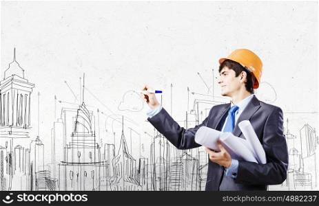 Urban construction. Young man engineer in helmet drawing construction project