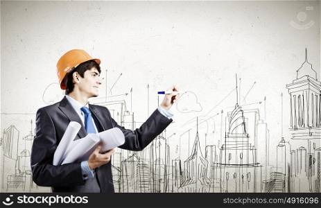Urban construction. Young man engineer in helmet drawing construction project