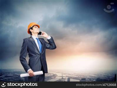 Urban construction. Young man engineer talking on mobile phone