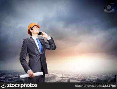 Urban construction. Young man engineer talking on mobile phone