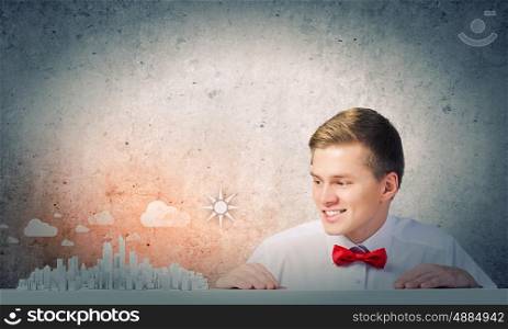 Urban construction. Young man pointing at modern city model