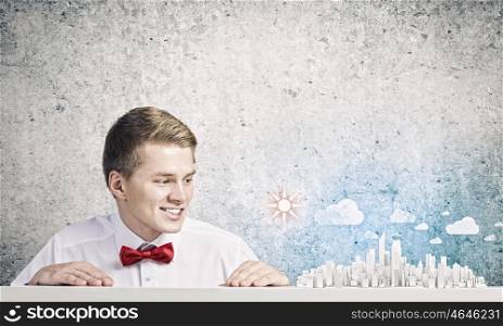 Urban construction. Young smiling businessman looking at city model