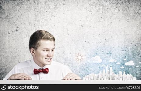 Urban construction. Young smiling businessman looking at city model