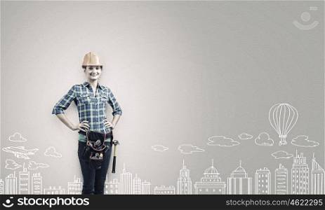 Urban construction. Young woman builder in hardhat wearing toolbelt