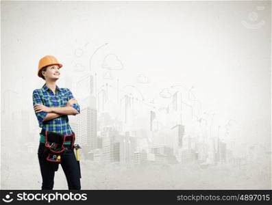 Urban construction. Young woman builder in hardhat wearing toolbelt