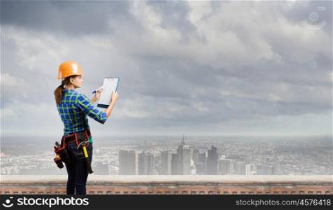 Urban construction. Young woman builder with folder in hand