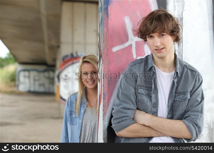 Urban couple stood by gratified wall