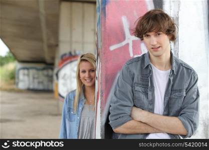 Urban couple stood by gratified wall