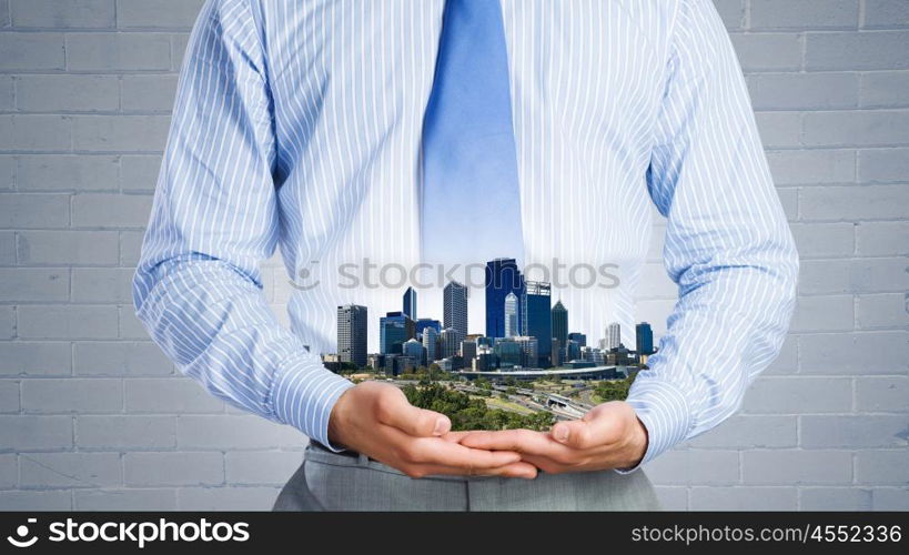 Urban development project. Close up of businessman holding city model in hands