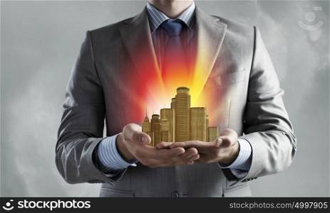 Urban development project. Close up of businessman holding city model in hands
