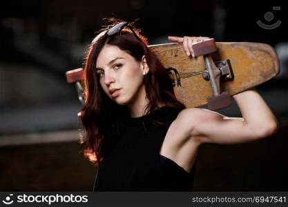 Urban fashionable girl with longboard posing outdoors in the city.. Urban fashionable girl with longboard posing outdoors in the city