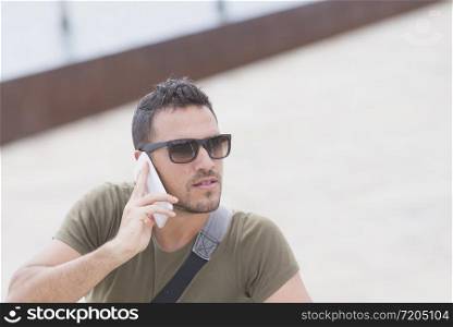Urban man using a phone wearing sunglasses outdoors